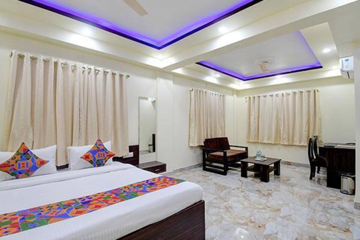 A hotel room with a bed, a desk, a chair, and a small table.