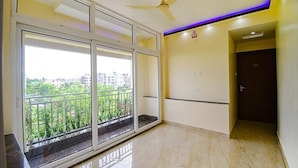 A spacious room with large sliding glass doors leading to a balcony, a ceiling fan, and a door with a handle.
