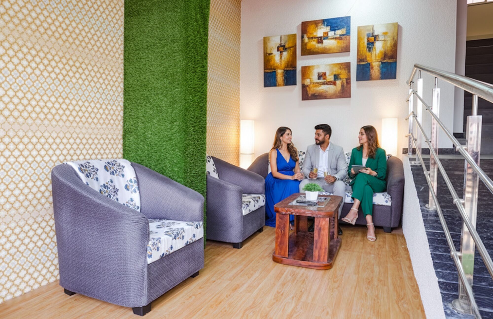 Un moderno vestíbulo con sofás tapizados en gris, una mesa de centro de madera y un jardín vertical verde. Hay pinturas abstractas en la pared y una escalera a la derecha.