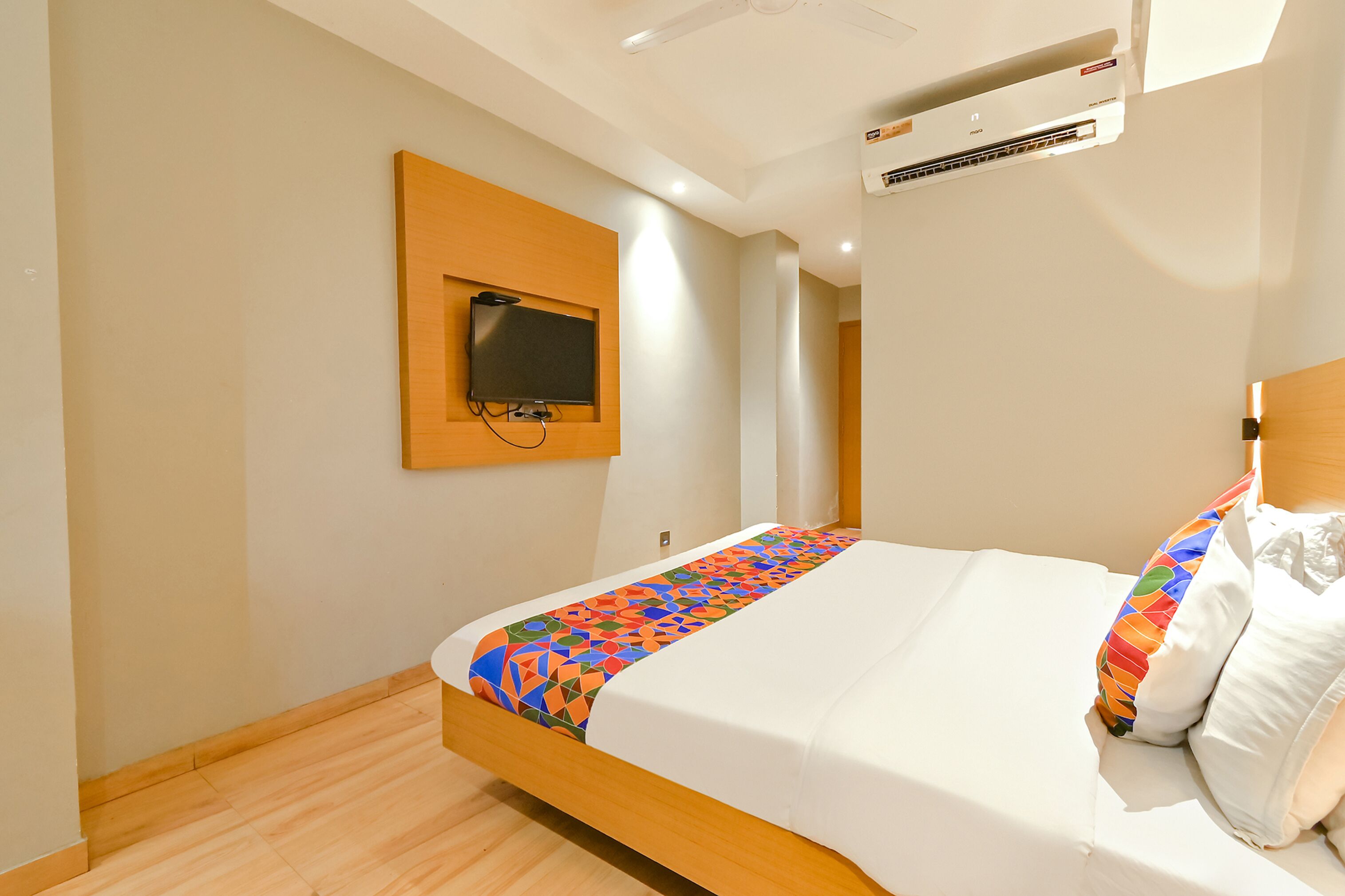 Ein Hotelzimmer mit einem Bett, einem Wandfernseher und einer Klimaanlage.