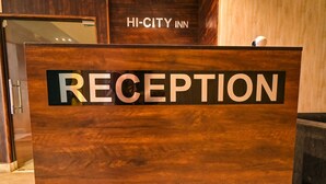 A reception desk with a wooden finish and the words "RECEPTION" prominently displayed. - FabHotel Penthouse (Guwahati)
