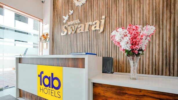 A reception desk with a wooden backdrop and a sign for 'Hotel Swaraj'. - Fabhotel Swaraj (Palghar)