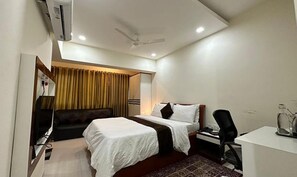 A hotel room with a bed, a desk, a chair, and a TV.