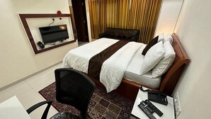 A hotel room with a bed, a desk with a chair, a TV mounted on the wall, and a telephone. - Fabhotel Prime Finesse (Pune)
