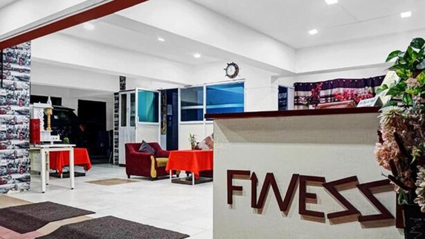 A reception area with a 'FWESS' sign, a clock, and a red sofa. - Fabhotel Prime Finesse (Pune)