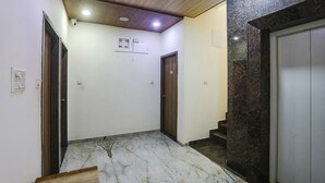 A hallway with a marble floor, a ceiling fan, and a door with the number 304. - Fabhotel Vedanta Inn (Nagpur)