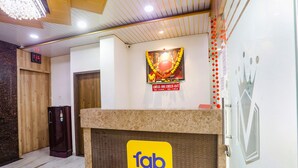 A hotel reception area with a check-in counter, a digital clock, and a decorative wall with a 'Check-In' sign. - Fabhotel Vedanta Inn (Nagpur)