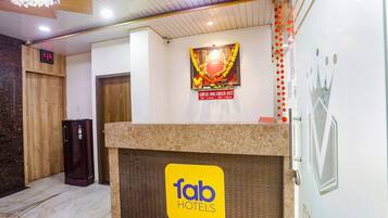 A hotel reception area with a check-in counter, a digital clock, and a decorative wall with a 'Check-In' sign.