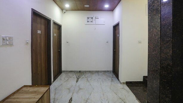 A hallway with wooden doors, a marble floor, and a ceiling with recessed lighting. - Fabhotel Vedanta Inn (Nagpur)