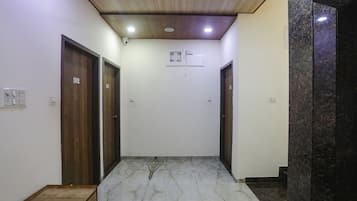 A hallway with wooden doors, a marble floor, and a ceiling with recessed lighting.