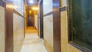 A corridor with marble walls and a wooden door. - FabHotel Trish The Gera (New Delhi)
