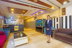A hotel lobby with a reception desk, seating area, and a fish tank. - FabHotel Trish The Gera (New Delhi)