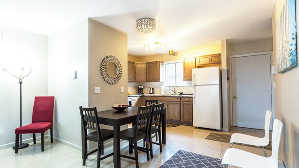A compact kitchen with wooden cabinets, a refrigerator, and a dining area with a table and chairs. - Cozy Mountain Getaway: Perfect for Families, Groups and Pets (Tannersville)