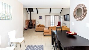 A modern living room with a fireplace, a dining area with a black table, and a red chair. - Cozy Mountain Getaway: Perfect for Families, Groups and Pets (Tannersville)