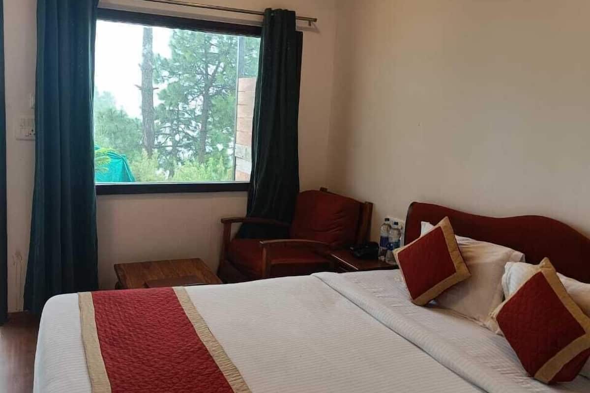 A hotel room with a bed, a desk, a chair, a window with curtains, and a ceiling fan.