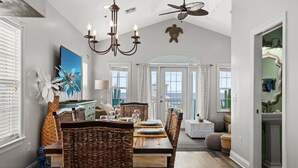 A spacious dining area with a large table, wicker chairs, and a chandelier. - Sea-Jay ~ Dog-Friendly Gulf View Retreat, Steps to Beach & Pier Park (Panama City Beach)