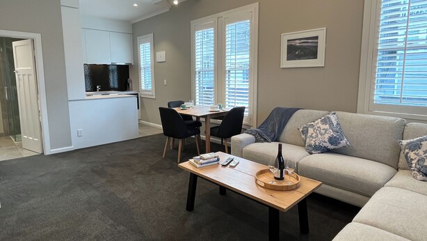 A modern living room with a sofa, a coffee table, and a dining area. - Tinakori Village Retreat - 
Renovated apartment in a charming heritage building (Wellington)