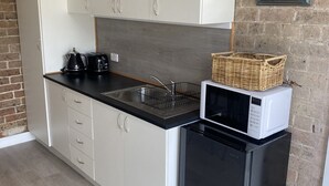 Une cuisine avec des meubles blancs, un plan de travail noir, un four à micro-ondes et un réfrigérateur.