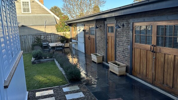 Un patio extérieur moderne avec une terrasse en bois, une petite pelouse et un mur en briques.
