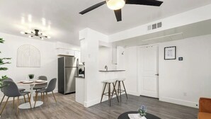 Una cucina moderna con mobili bianchi, un frigorifero in acciaio inossidabile e un'area pranzo con un tavolo rotondo e sedie.