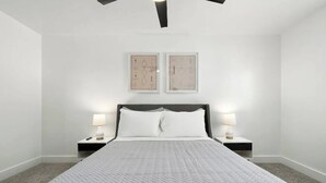 Una camera da letto moderna con un letto grande, due lampade da comodino e due opere d'arte astratte incorniciate a parete.