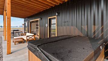 A covered outdoor area with a pool table, wooden benches, and a door leading to a building.
