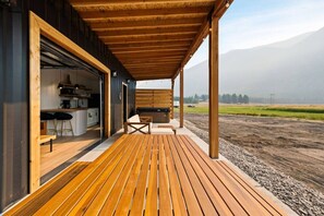 Um deck de madeira com cozinha e área de estar ao ar livre.