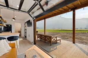 A modern interior with a kitchen, dining area, and a large window overlooking a field.