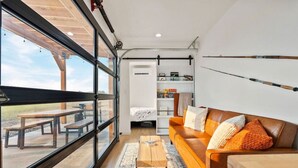 Ein modernes Wohnzimmer mit großem Fenster, einem braunen Ledersofa, einem Holztisch und einem Bücherregal.