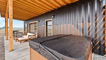 A pool table under a wooden roof with outdoor seating and a view of the countryside.