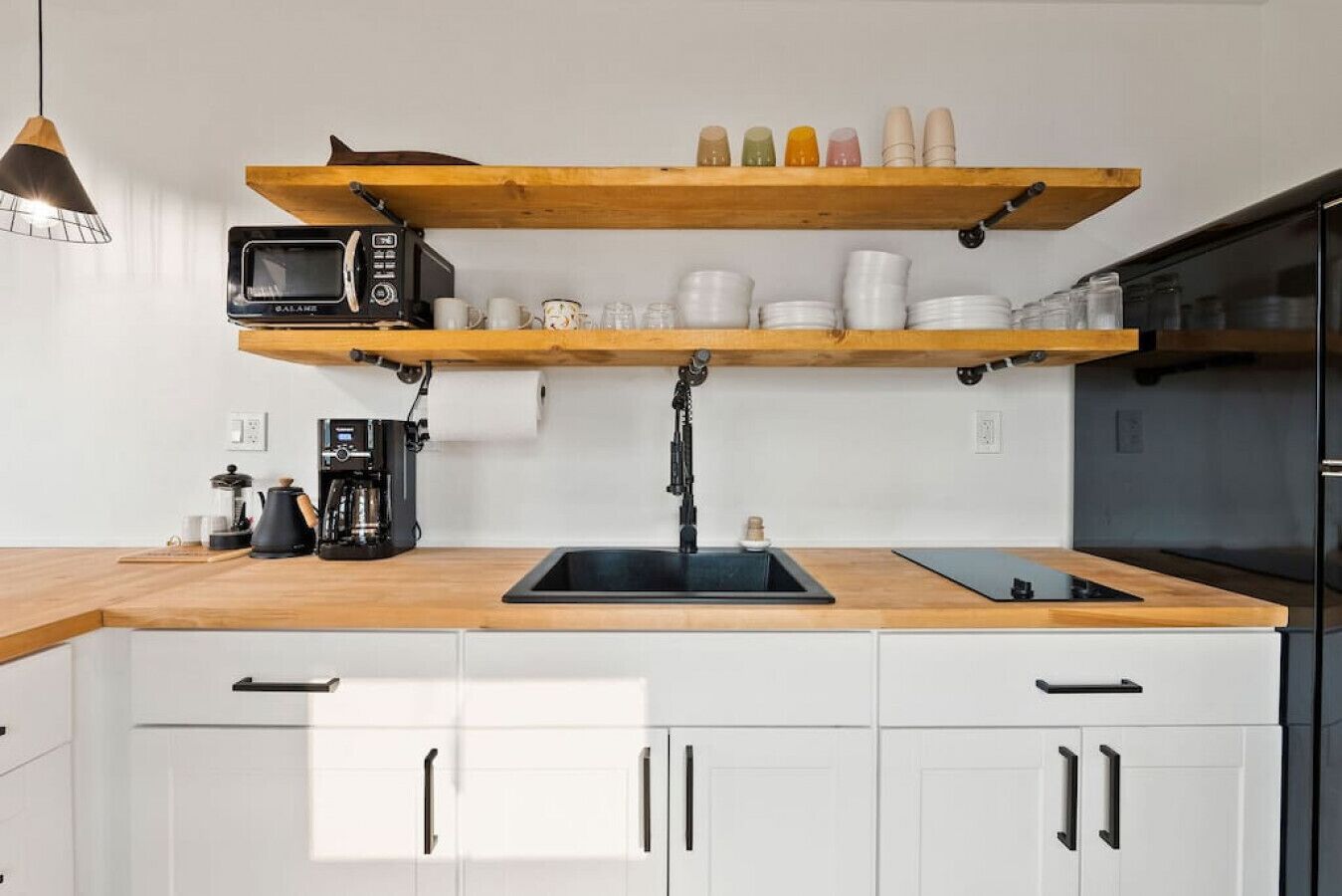 Uma cozinha moderna com bancadas de madeira, uma pia preta e uma máquina de café.