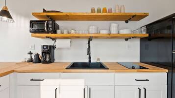 Uma cozinha moderna com bancadas de madeira, uma pia preta e uma máquina de café.