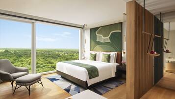 Un dormitorio moderno con una cama grande, vistas al verdor exterior, un separador de madera y una silla.