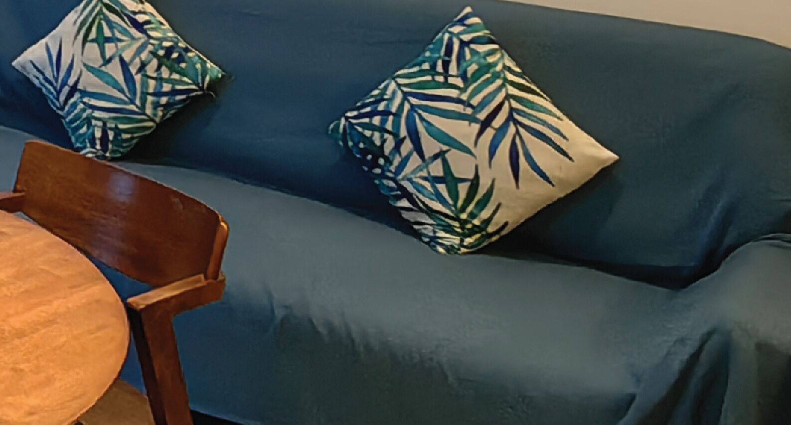 Ein blaues Sofa mit zwei Zierkissen und einem Holzsessel.