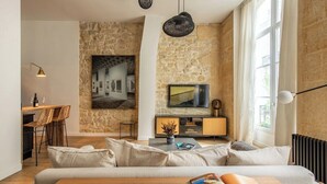 Una sala de estar moderna con una pared de acento de piedra, un televisor de pantalla plana grande y una zona de estar acogedora con un sofá y una mesa de centro.