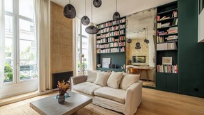 Una sala de estar moderna con un sofá color beige, una mesita de centro y una estantería llena de libros.