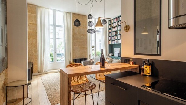 Una cocina moderna con una isla de madera, electrodomésticos negros y una estantería.