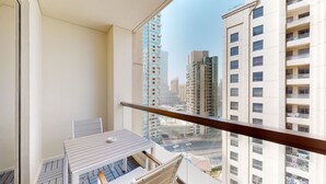 A balcony with a table and chairs, overlooking a cityscape with tall buildings. - Glamorous Upgraded 2 Bed l Close to JBR & Beach (Jumeirah Beach Residence)