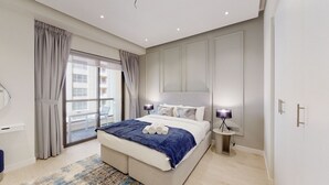 A modern bedroom with a large bed, a nightstand, a lamp, and a view of the outside balcony. - Glamorous Upgraded 2 Bed l Close to JBR & Beach (Jumeirah Beach Residence)