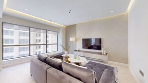 A modern living room with a large sofa, a TV, and a coffee table. - Glamorous Upgraded 2 Bed l Close to JBR & Beach (Jumeirah Beach Residence)