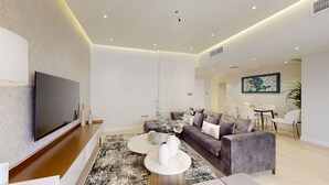 A modern living room with a flat-screen TV, a grey sofa, two round coffee tables, and a black-and-white rug. - Glamorous Upgraded 2 Bed l Close to JBR & Beach (Jumeirah Beach Residence)