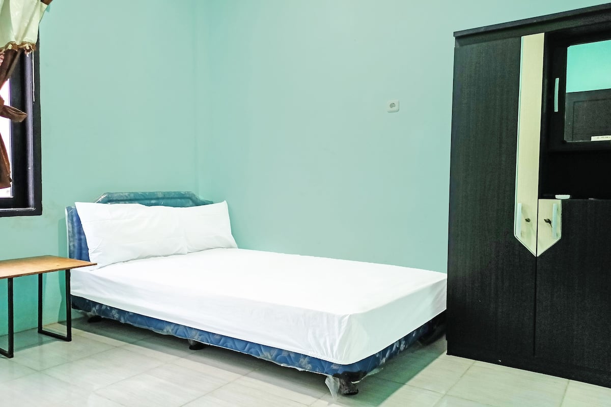 Ein Zimmer mit einem Einzelbett, einem kleinen Tisch und einem Kleiderschrank.