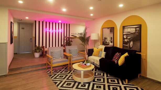 Un salon moderne avec un papier peint à rayures, un néon et un canapé noir et jaune.