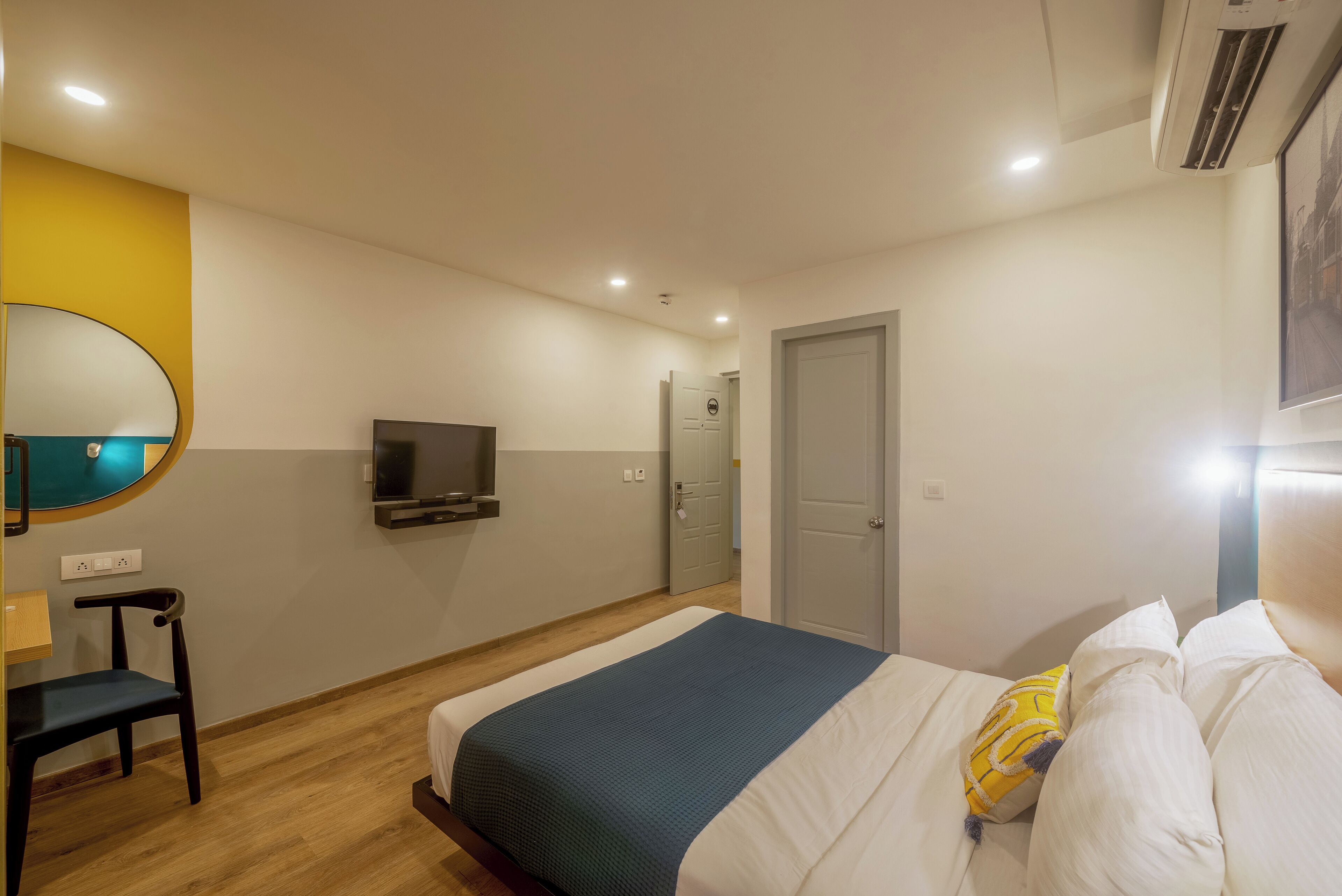 Een slaapkamer met een bed, een televisie, een spiegel en een deur.
