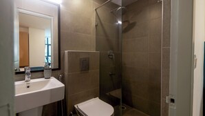 Une salle de bain avec un lavabo blanc, des toilettes et une douche à parois de verre.