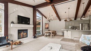 Ein geräumiges Wohnzimmer mit Kamin, Fernseher, Sofa und Essbereich.