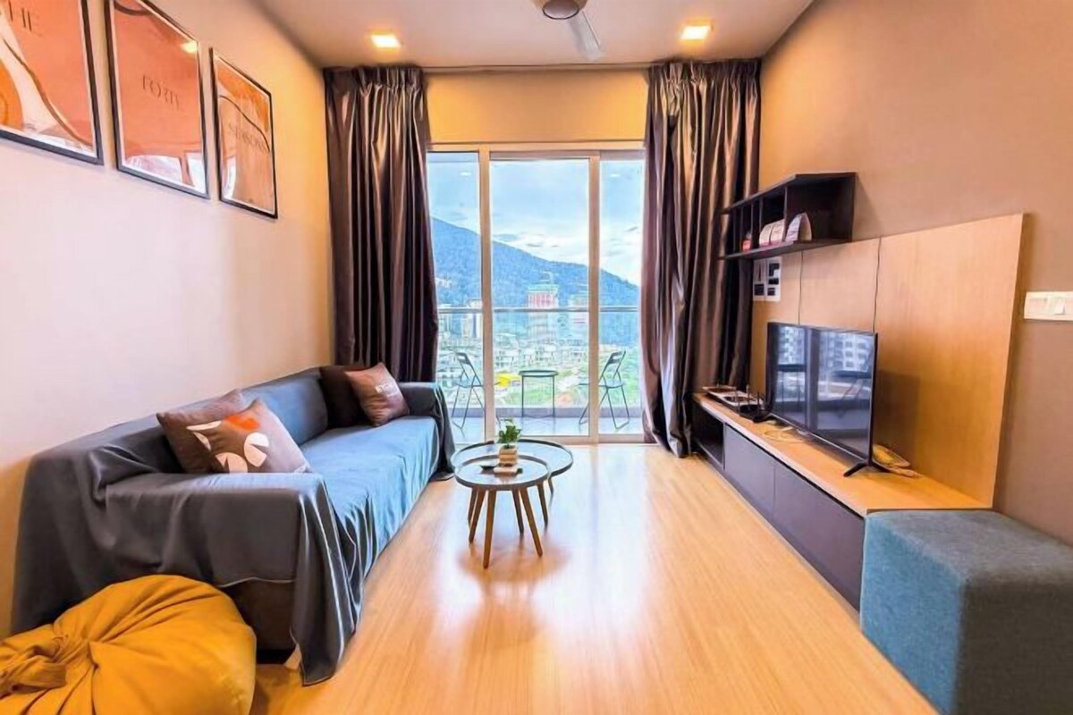 A modern living room with a sofa, a small round table, a TV, and a view of a cityscape through large windows.