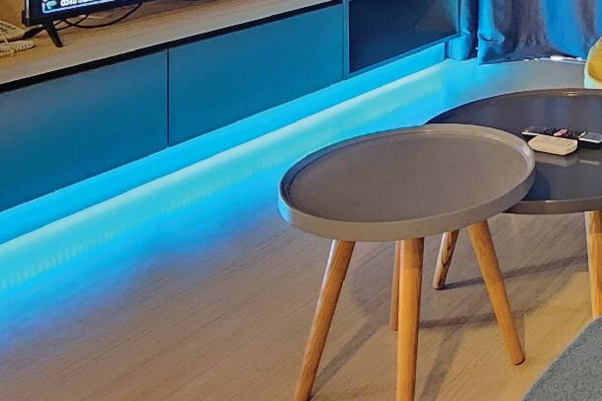 A modern living area with a kitchen counter, a round table, and a sofa with a fluffy pillow.