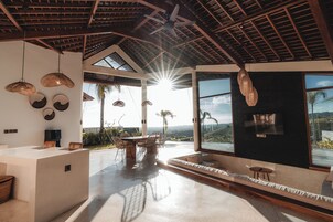 Una habitación amplia con un gran ventanal, un ventilador de techo y un comedor con mesa y sillas.