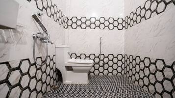 A bathroom with a toilet, a shower, and a sink.